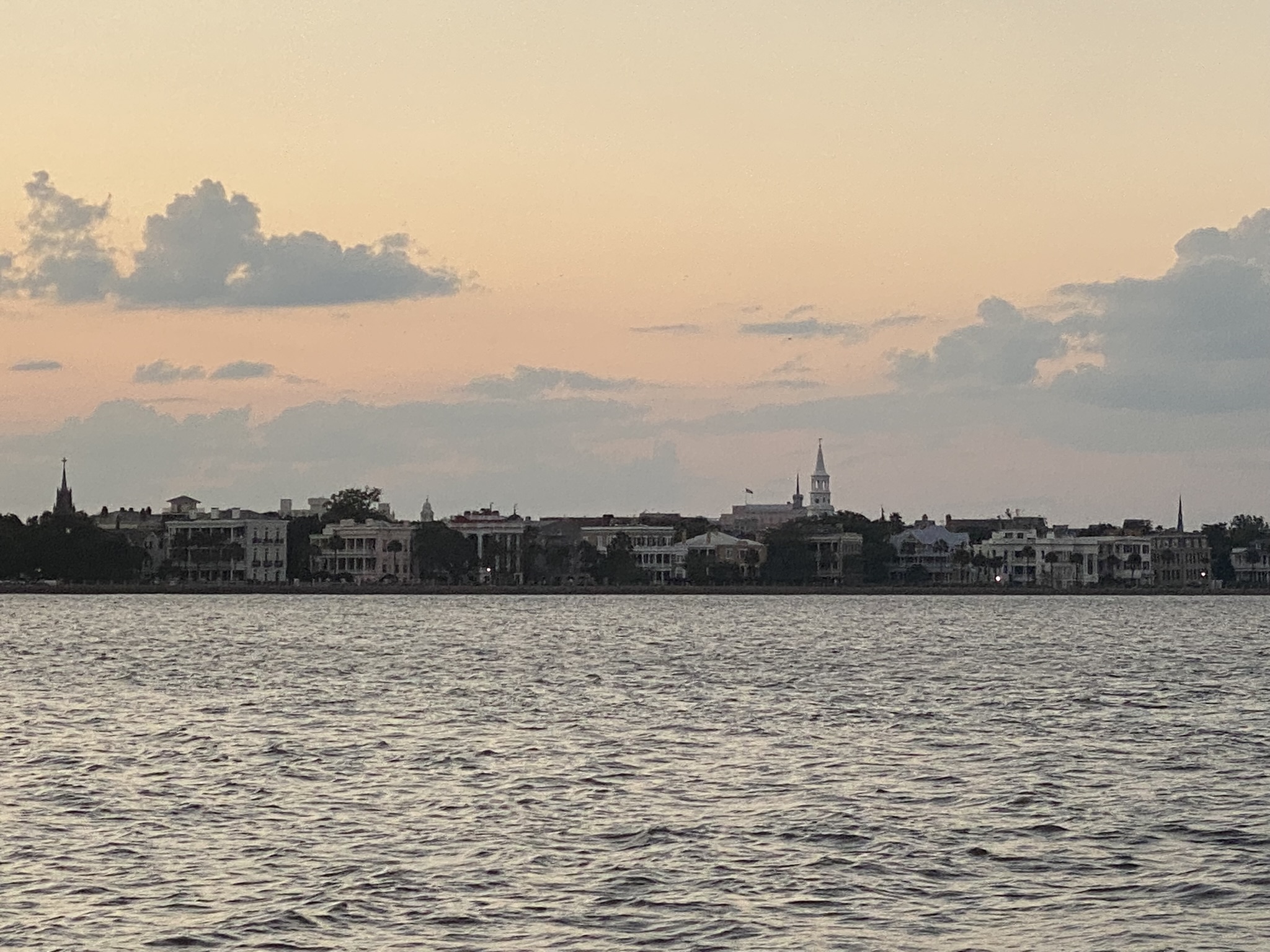 Outline of downtown Charleston, South Carolina as the sun is setting as seen from a boat in the bay