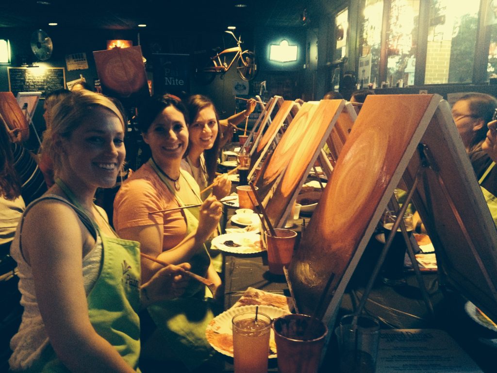 Three women painting at Paint Night in Charleston, South Carolina at Two Keys Tavern