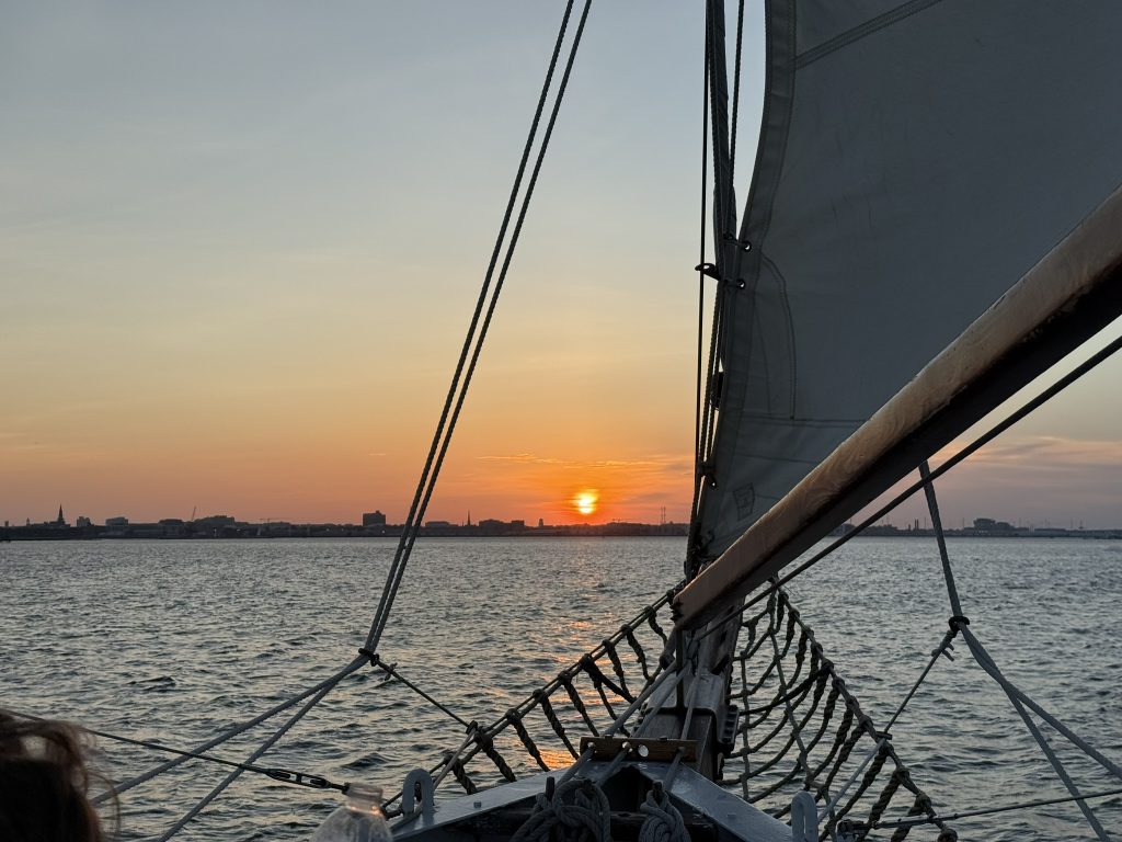 The front end of a sail boat while riding through the Charleston, SC harbor near sunset.