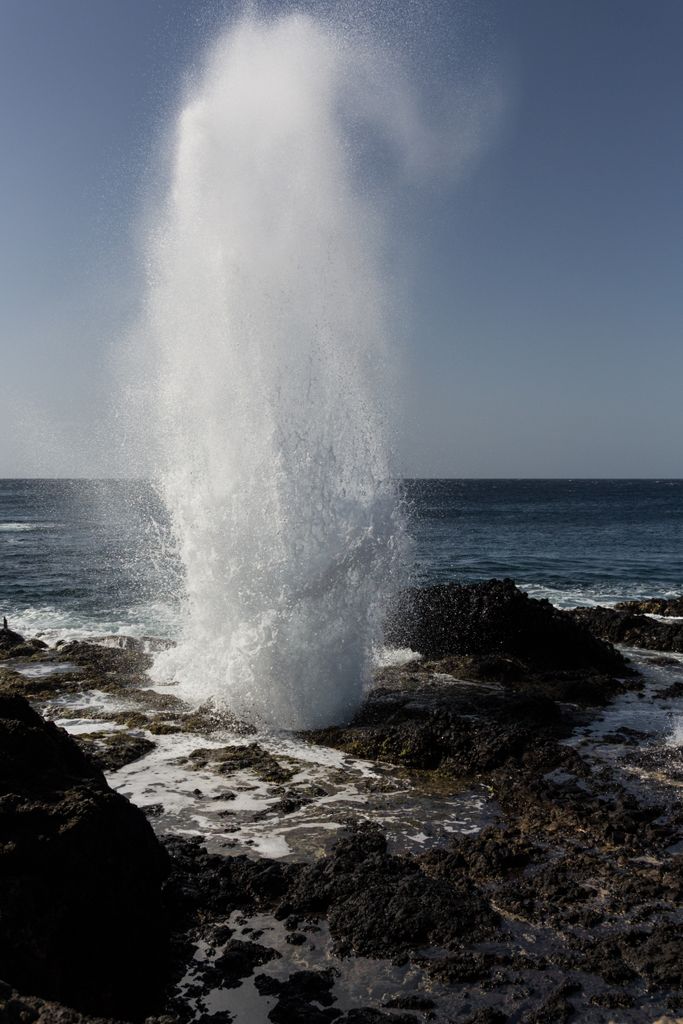 Powerful geyser erupting by the sea, creating a breathtaking natural spectacle on a rocky coastline of Grand Cayman's East end.