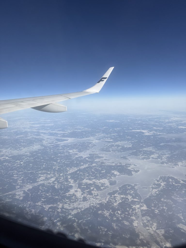 Looking out of the window to see snowy Finland below and the tip of the Finnair plane wing out of the window.