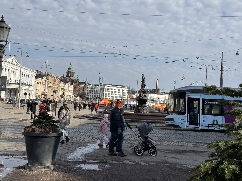 In Helsinki, Finland, near the Market Square, people are walking and exiting the tram.