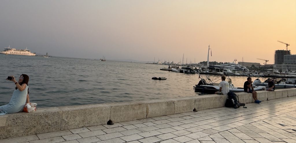 Split harbor waterfront at sunset with a Jadrolinija ferry heading out to sea